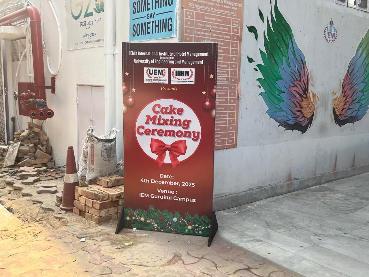Printed event standee placed beside a painted mural at a campus venue entrance