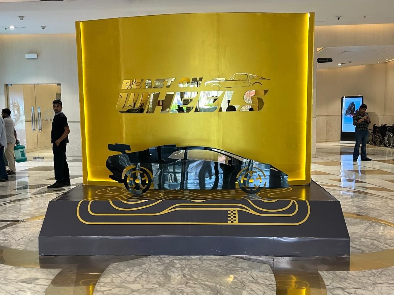 Gold backdrop automotive display installation with a track-printed plinth inside a mall