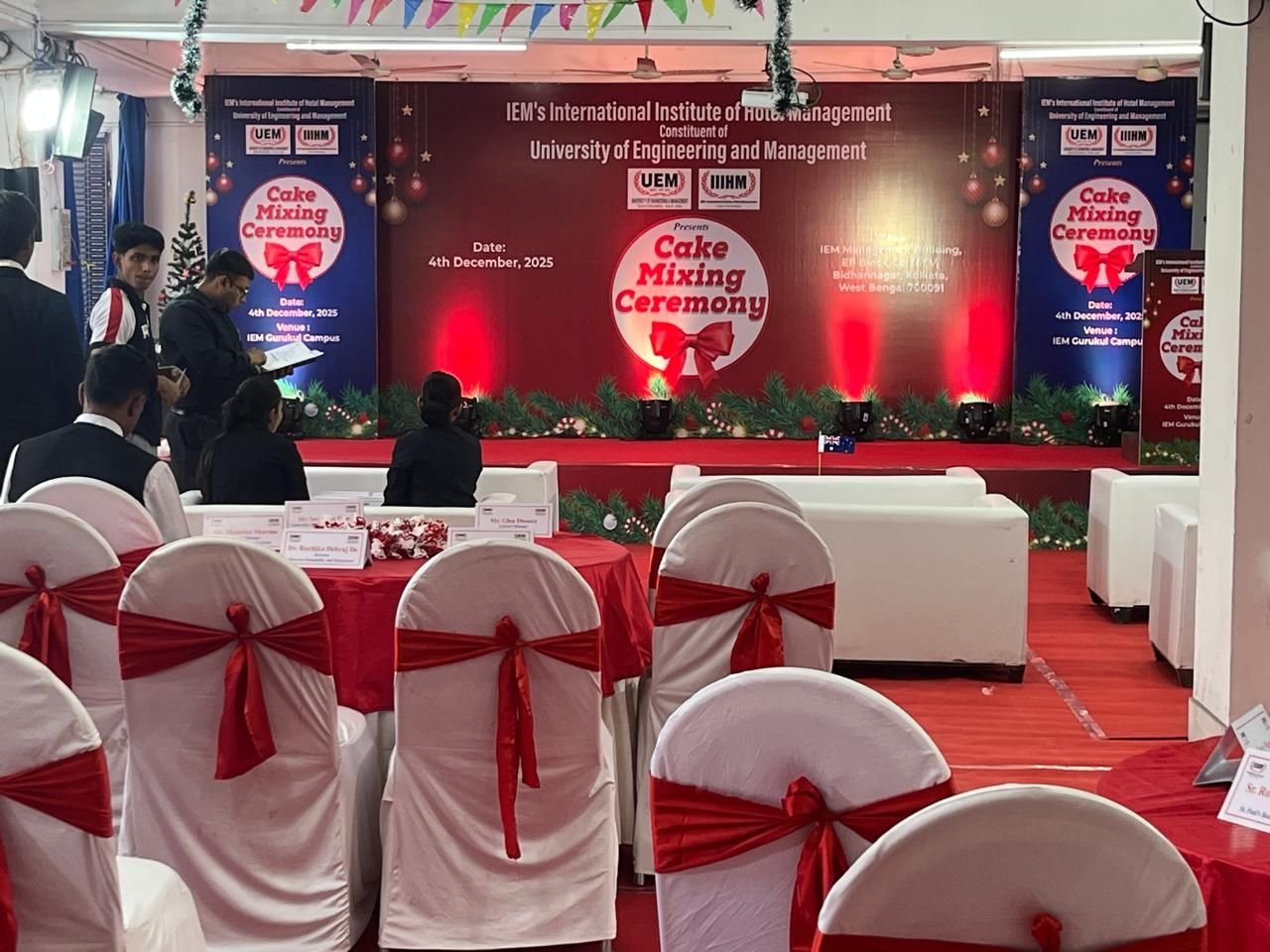 Ceremony hall with red chair covers, bunting and a branded stage backdrop