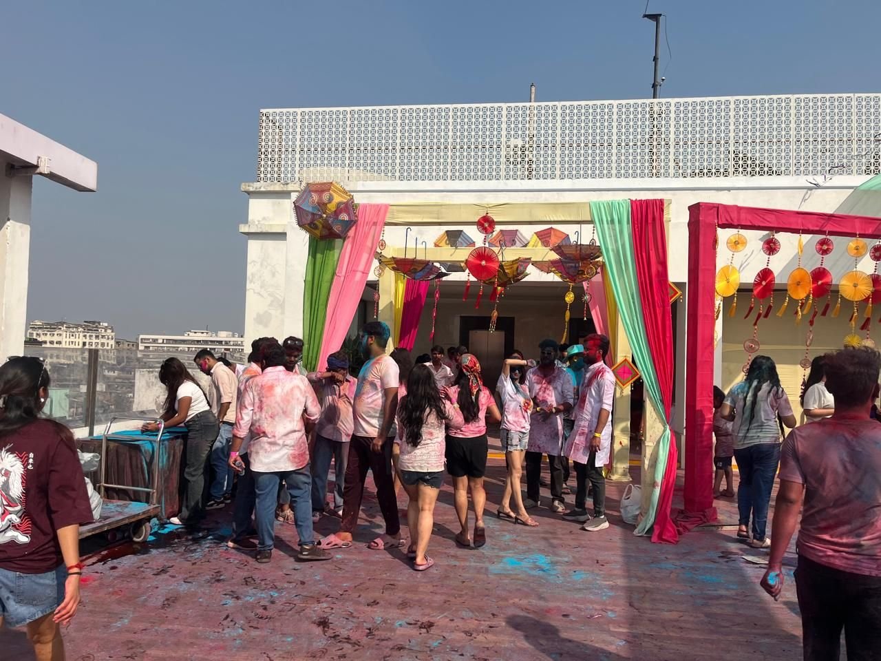 Decorated festival entry with balloons, drapes and guests arriving on a rooftop