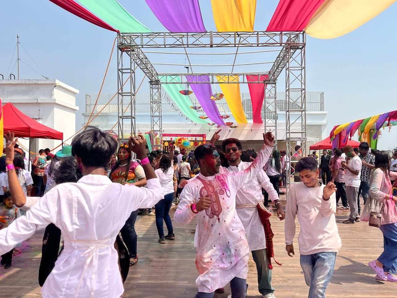 Guests dancing on an open-air dance floor beneath a truss rig and coloured fabric