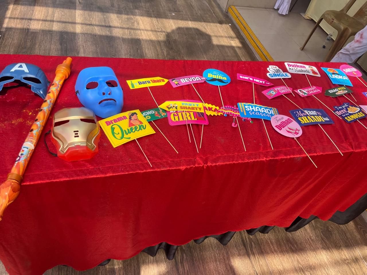 Photo-booth props and masks laid out on a red table for guest engagement
