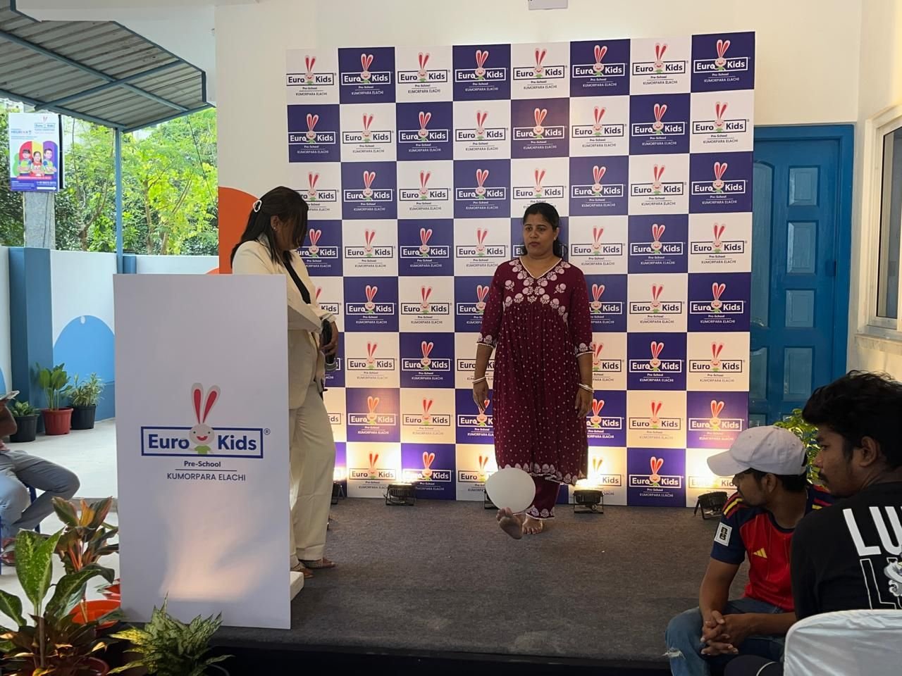 Anchored segment in front of a branded step-and-repeat backdrop with podium at a school event